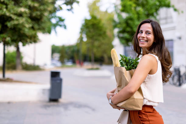 istock Woman smiling and glancing back with grocery bag 2168360722