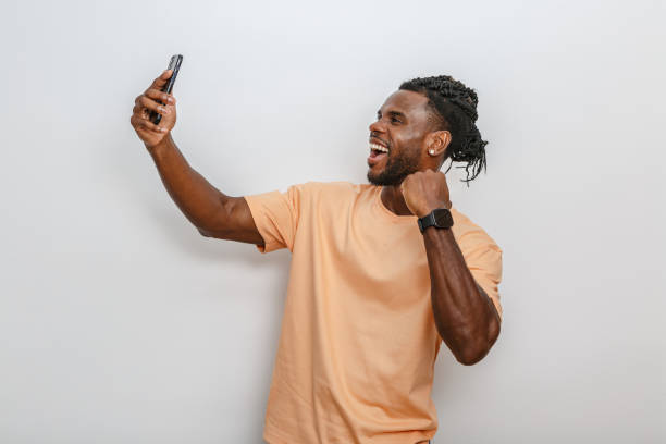 istock Man taking a selfie smiling and celebrating on a well-lit white background 2168360736