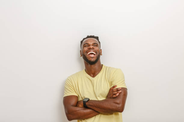 istock Joyful Man Laughing With Arms Crossed Against a Plain Wall in Natural Light 2168360764