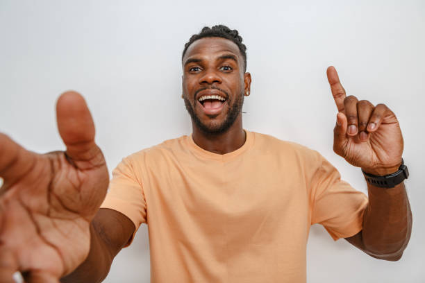 istock Young man enthusiastically gesturing with arms extended in a light-colored shirt against a neutral background 2168360912