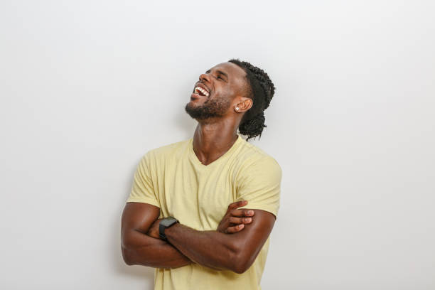 A man laughing joyfully with crossed arms in a simple indoor setting