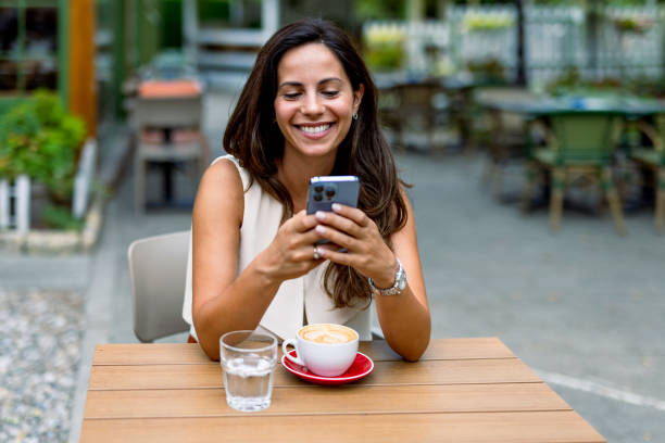 istock Woman checking her phone at an outdoor cafe table 2168361202