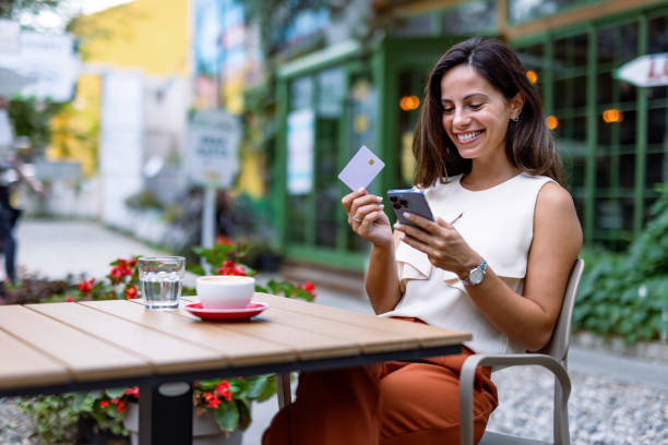 Woman in cafe looking at smartphone holding a card