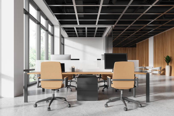 istock Modern office workspace with desks, monitors, and computers, featuring light wood accents, bright windows. Concept of contemporary professional workstations. 3D rendering 2168367251