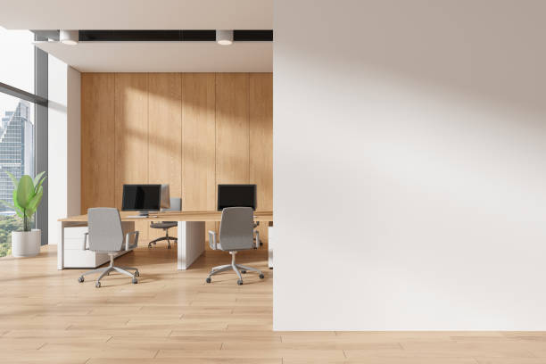 istock Modern office interior with desks and chairs, wooden wall paneling, large windows, and a bright empty white wall, concept of workspace mockup. 3D Rendering 2168367609