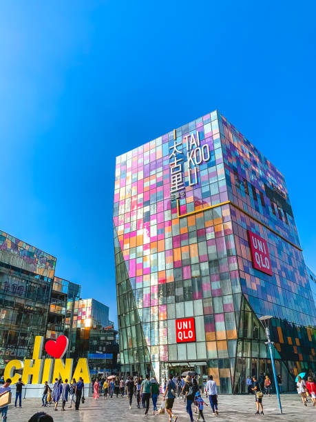 Beijing, China - September 21, 2019. The vibrant Taikoo Li Sanlitun shopping district in Beijing, China, comes alive under a clear blue sky. A large I Love CHINA sign stands prominently in the plaza, while the colorful facade of the Taikoo Li building and the well-known UNIQLO store draw crowds of shoppers and visitors.