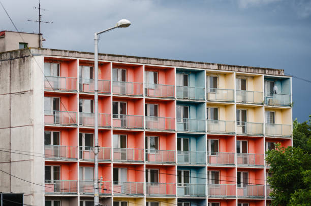 A multi-story apartment building featuring a series of balconies painted in vibrant colors, including shades of red, blue, and yellow. The building's geometric design is enhanced by the contrasting colors, creating a visually striking urban scene.