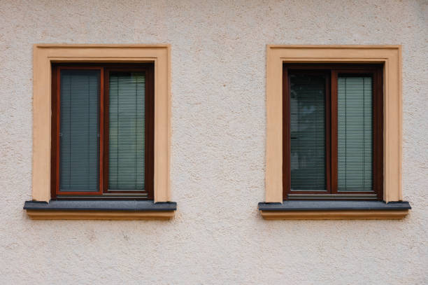 A row of ornate windows on a weathered yellow facade of an old building. The peeling paint and faded colors reveal the age of the structure, while the detailed window frames add an element of architectural elegance.