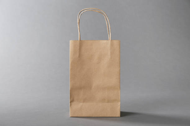 istock One kraft paper bag on grey background. Mockup for design 2168382759
