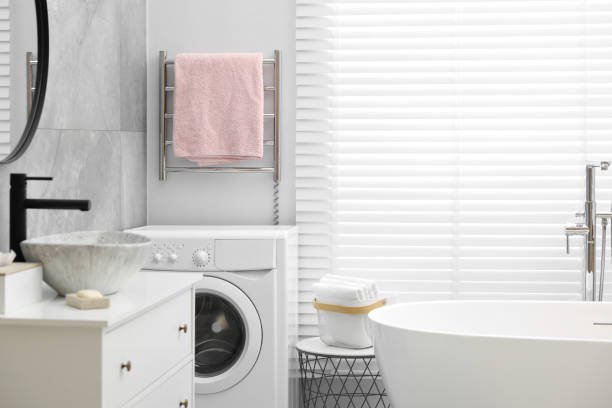 istock Stylish bathroom interior with heated towel rail and modern white tub 2168383201