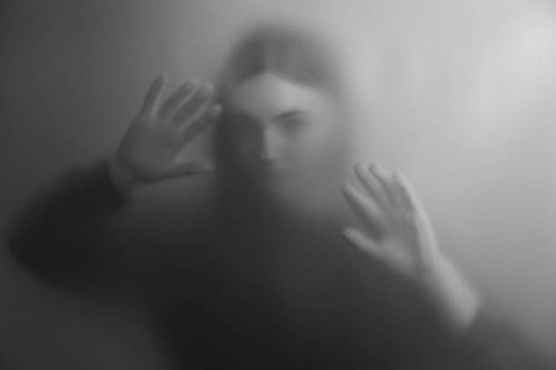 Silhouette of ghost behind fabric against light grey background. Black and white effect