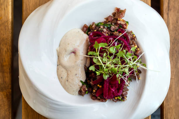 tar tar meat and vegetable salad in plate on wooden table in local outdoor cafe in Zelenogradsk town in Kaliningrad Oblast, Russia
