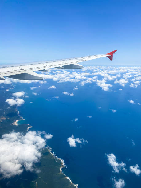 airplane wing and aerial view of blue sea coastline on sunny day through window during flight, Turkey