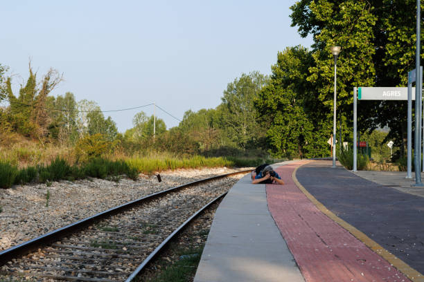 Photographer lying on the ground looking for a different perspective on the railway platform in Agres, Spain