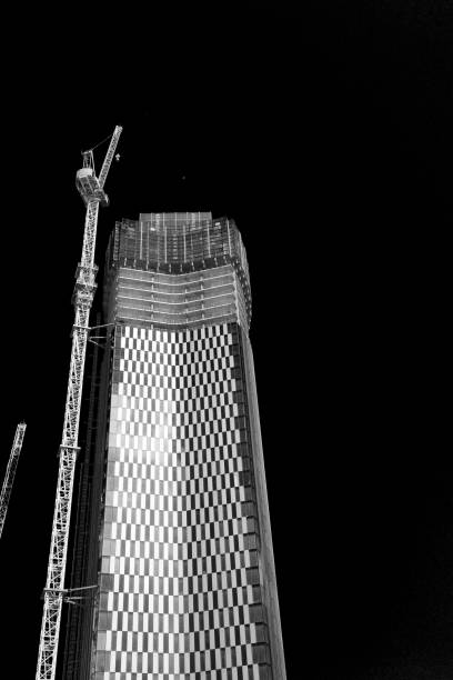 A Black and white photo of a tall modern building under construction at night.