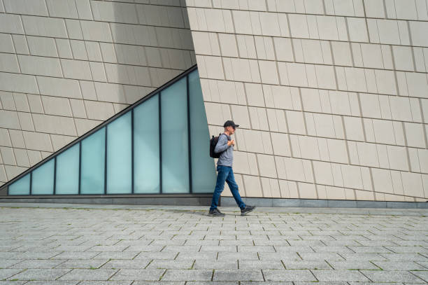 istock Man with a backpack walking past a modern building, exterior travel concept. 2168411861