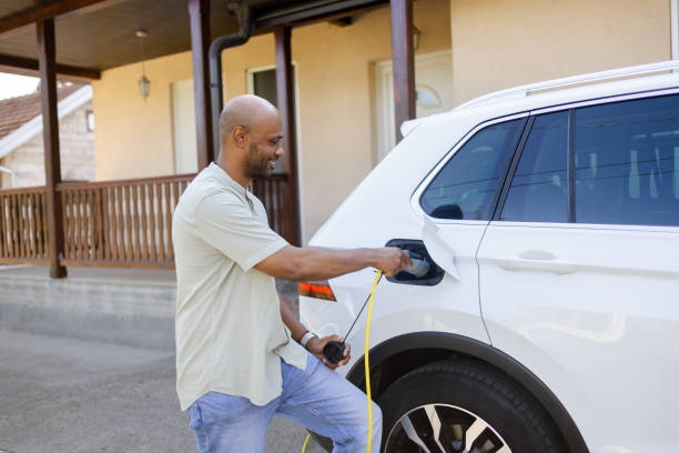 istock Latin man powers up his EV in front of his house 2168413652