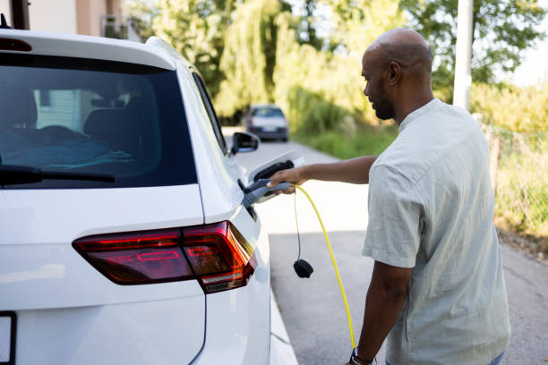 istock Latin man is charging his electric car on his front lawn 2168413684