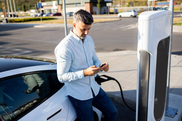 istock Man powers up his EV and surfing the net 2168413883