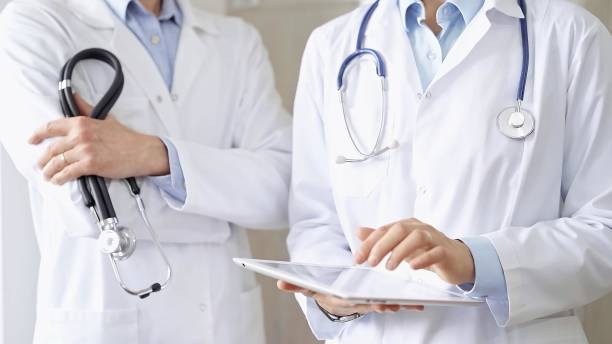 istock Two doctors wearing white coats and stethoscopes, using a digital tablet, discussing a patient's medical history. Medicine and science 2168417953