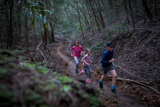 istock Family enjoy a run together through the forest 2168427578