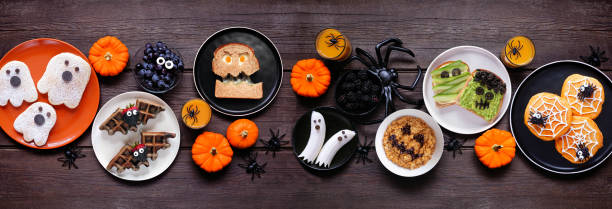 istock Spooky Halloween breakfast table scene over a dark wood banner background 2168430389
