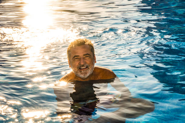 istock Happy mature man bathing in the pool at sunset 2168433221