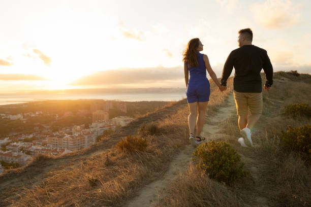istock Couple walking away on path at sunset overlooking city 2168436902
