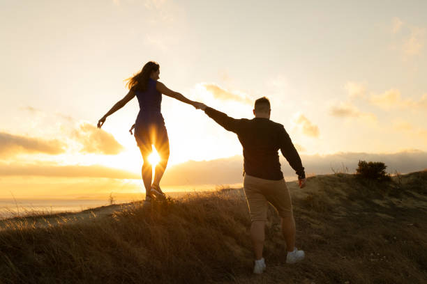 istock Loving couple walking on a hill at sunset holding hands 2168437039