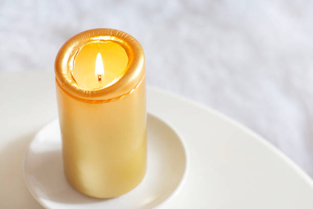 A golden candle stands on a white table
