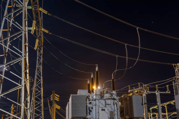 istock High voltage electrical transformer at power distribution station at night with industrial lighting. 2168443565