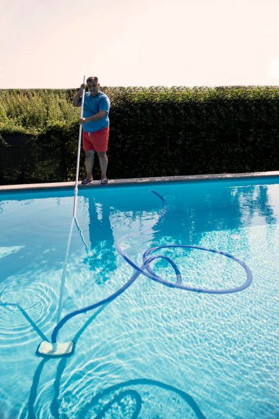istock Male pool cleaner cleaning a blue pool 2168443784