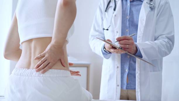 istock Doctor man is making notes on a clipboard while patient woman is describing back pain. Medicine and orthopedics concepts 2168444053
