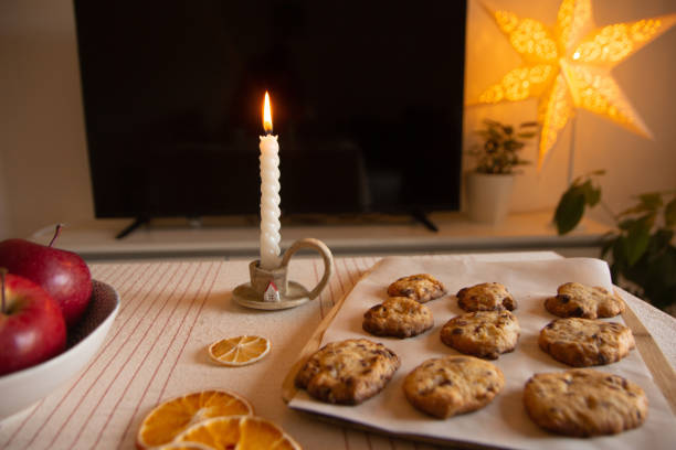 Christmas home still life. Christmas homemade cookies with cranberries and oranges and decor in the form of dried oranges and lemons, an apples, a burning candle in a candlestick and a Christmas lamp - star