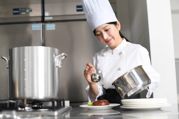 istock Asian young female cook making meat dish in the kitchen 2168448129