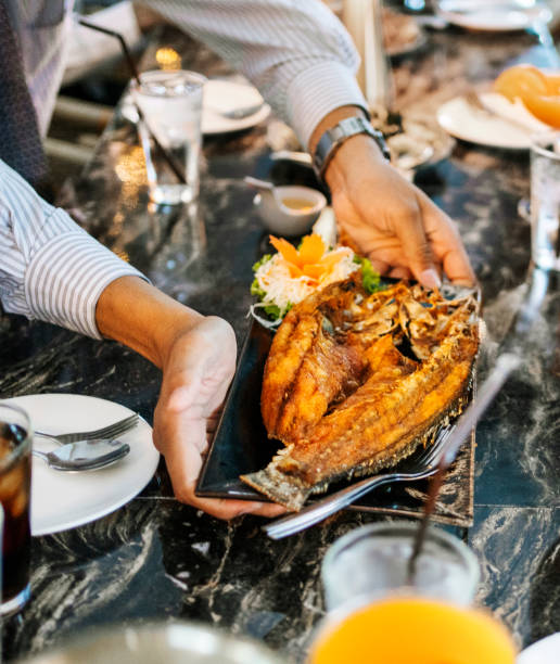 istock Close-up of waiter serving crispy fried fish on restaurant table 2168448265