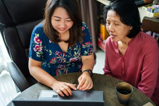 istock Young woman using laptop with mother by her side at home 2168452504