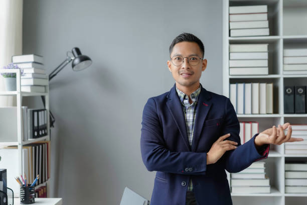 istock Young entrepreneur gesturing with one hand while standing in his office with crossed arms, looking confident and successful 2168455006