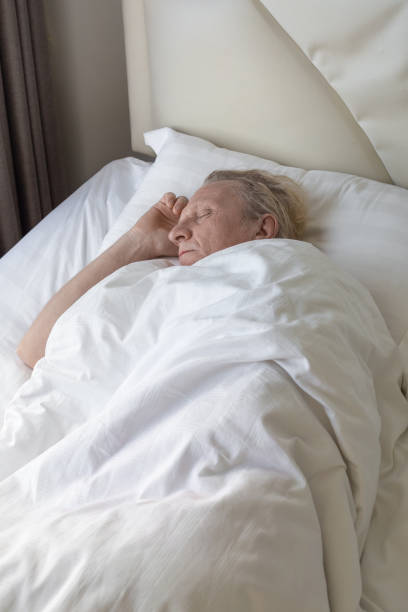 istock Sleeping mature man on a bed with white linen in his bedroom. Comfortable Rest and relaxation 2168456245