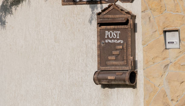 istock An old-fashioned brown mailbox on the side wall, with Post written in white lettering above it 2168456527