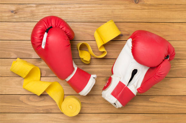 Red boxing gloves on wooden background, top view.