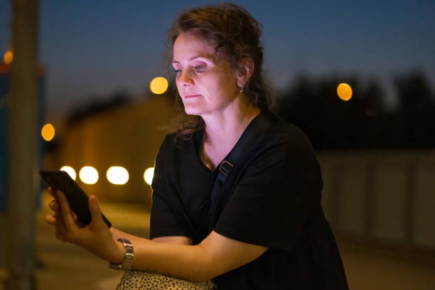 istock woman using mobile phone in outdoor setting, at evening 2168463720