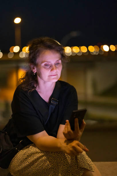 istock woman using mobile phone in outdoor setting, at evening 2168463722