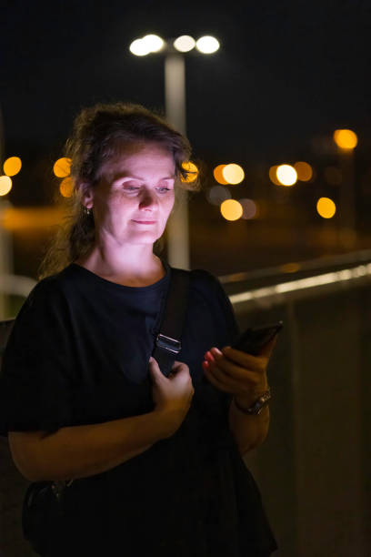 istock woman using mobile phone in outdoor setting, at evening 2168463781