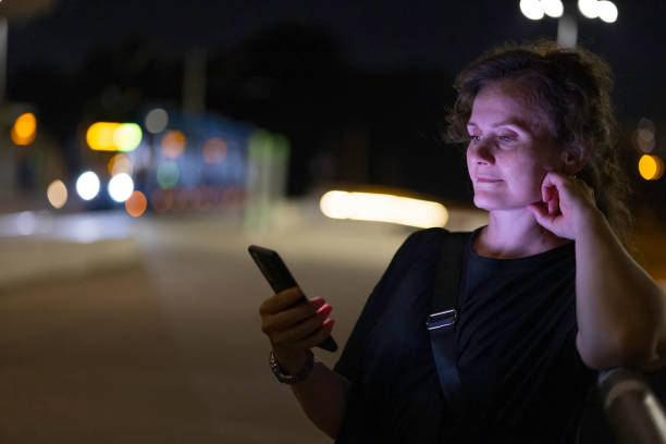 istock woman using mobile phone in outdoor setting, at evening 2168463796