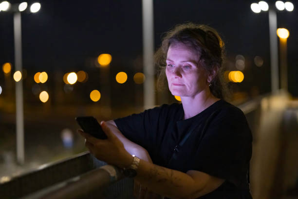istock woman using mobile phone in outdoor setting, at evening 2168463812