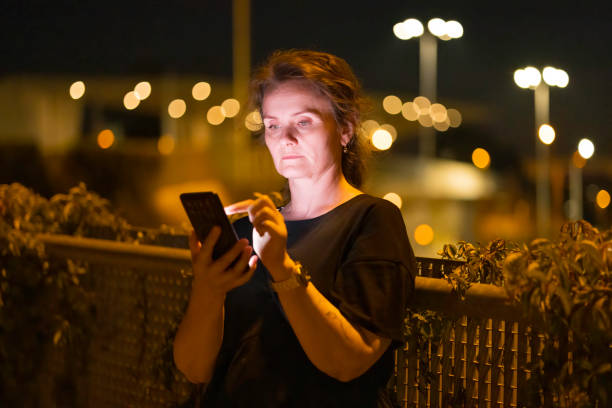 istock woman using mobile phone in outdoor setting, at evening 2168463865