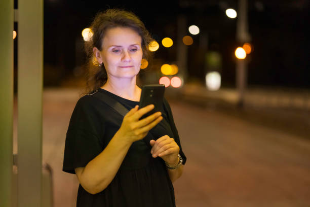 istock woman using mobile phone in outdoor setting, at evening 2168463895