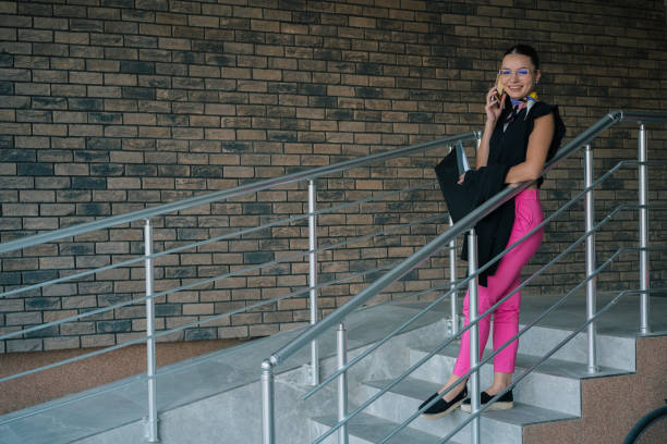 businesswoman is holding a stack of paperwork and using a mobile phone