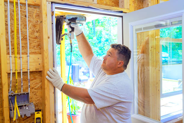 istock Carpenter is using pneumatic nail gun to install new front door for a new house 2168479164